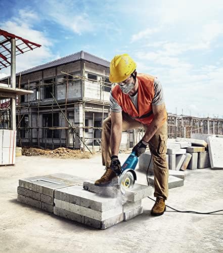 Worker using a circular saw on a concrete block at a construction site.